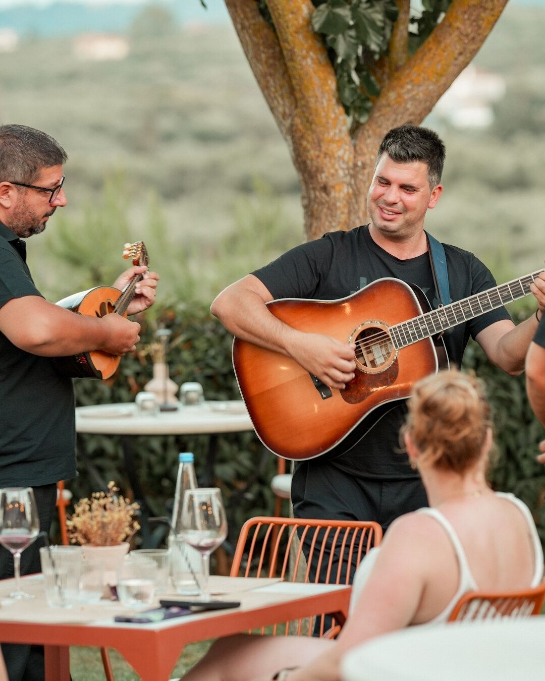 Musicians playing guitar and mandolin between the tables