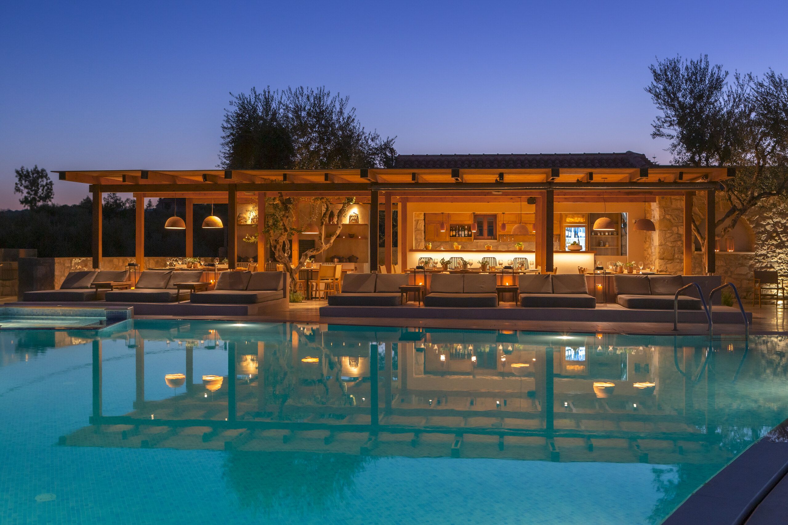 The pool bar lit up at dusk, reflected in the water