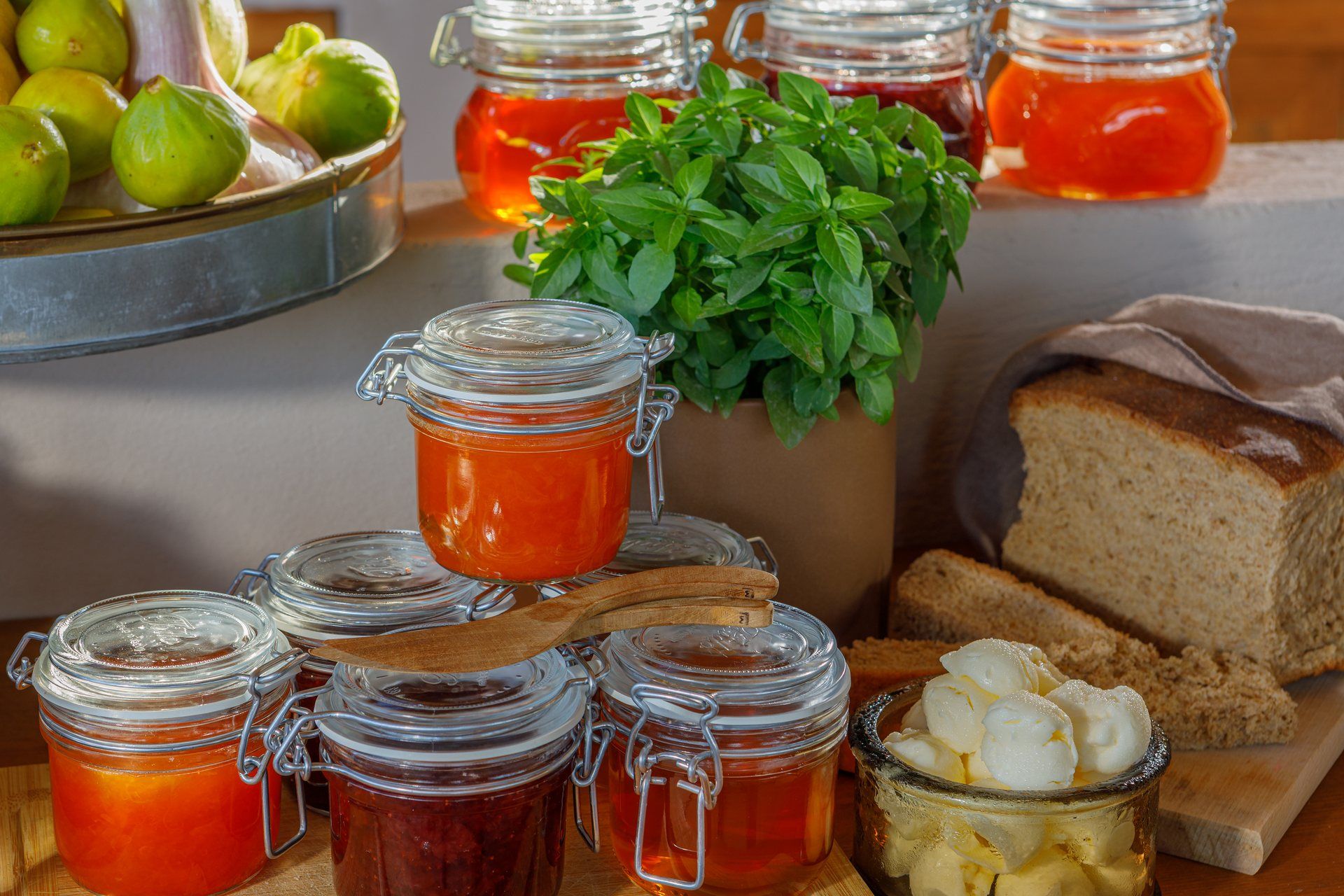 Homemade marmalades in glass jars, with fresh bread and butter