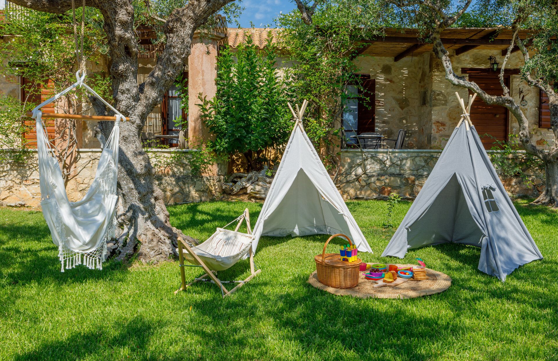 A hanging chair and children’s play tents on the grass in front of the houses
