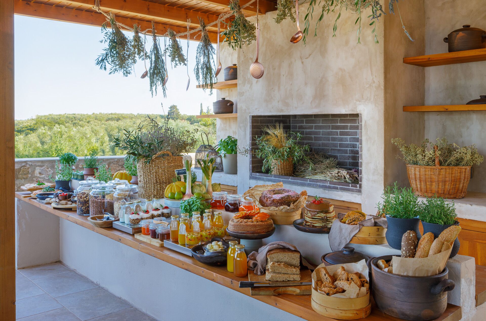 The breakfast buffet with breads, jams and fruit under hanging herbs