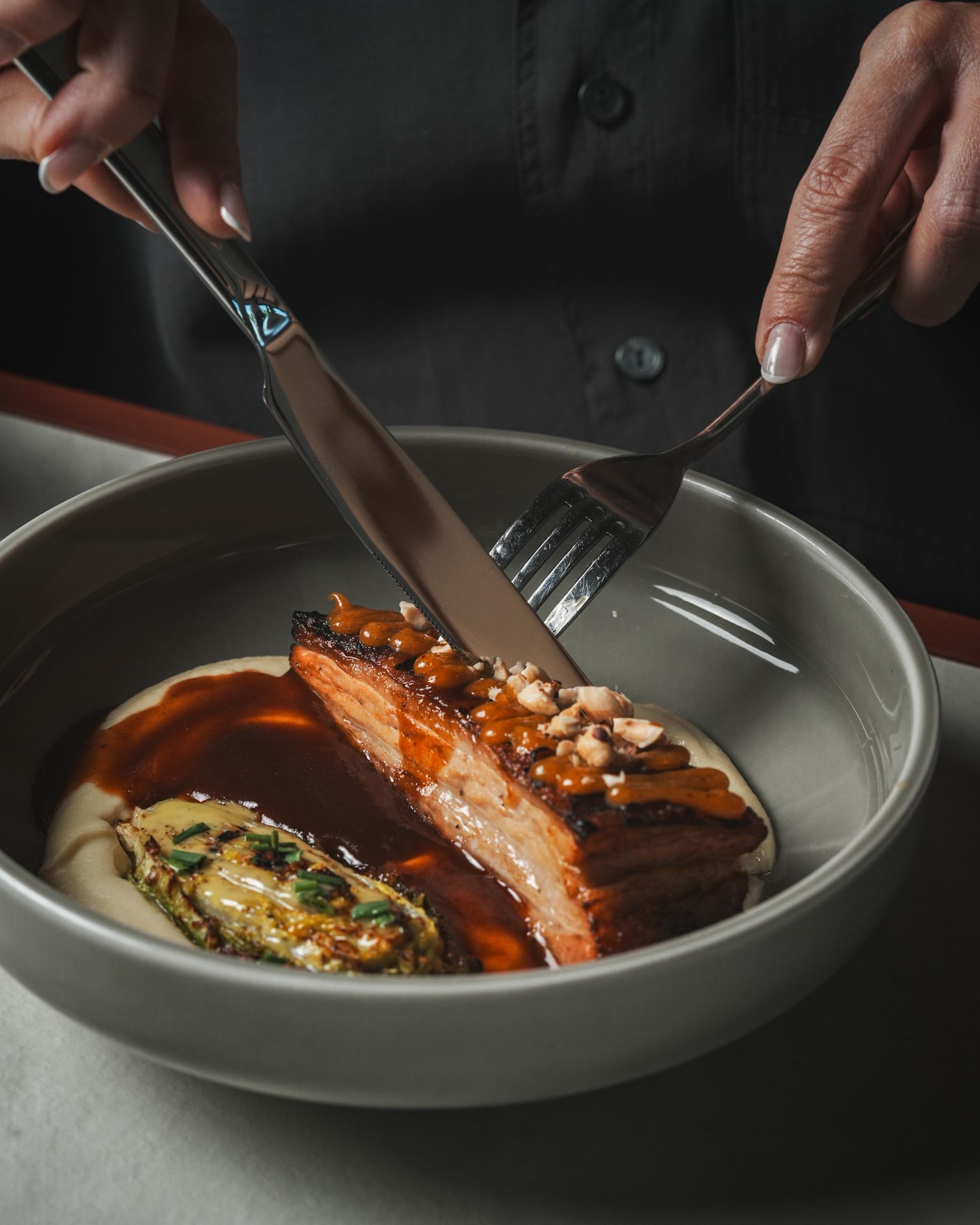 A dish of slow-cooked pork with hazelnuts being served at Meraki