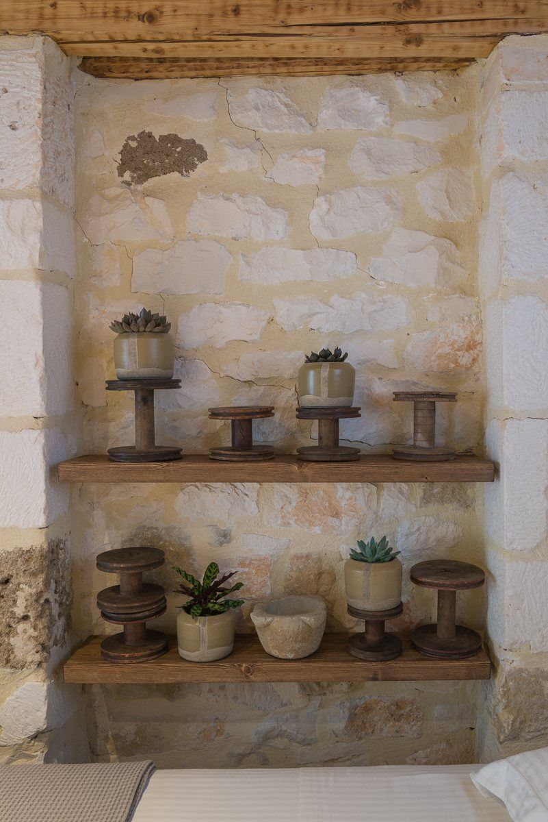 Old wooden spools and small plants on shelves in a stone niche
