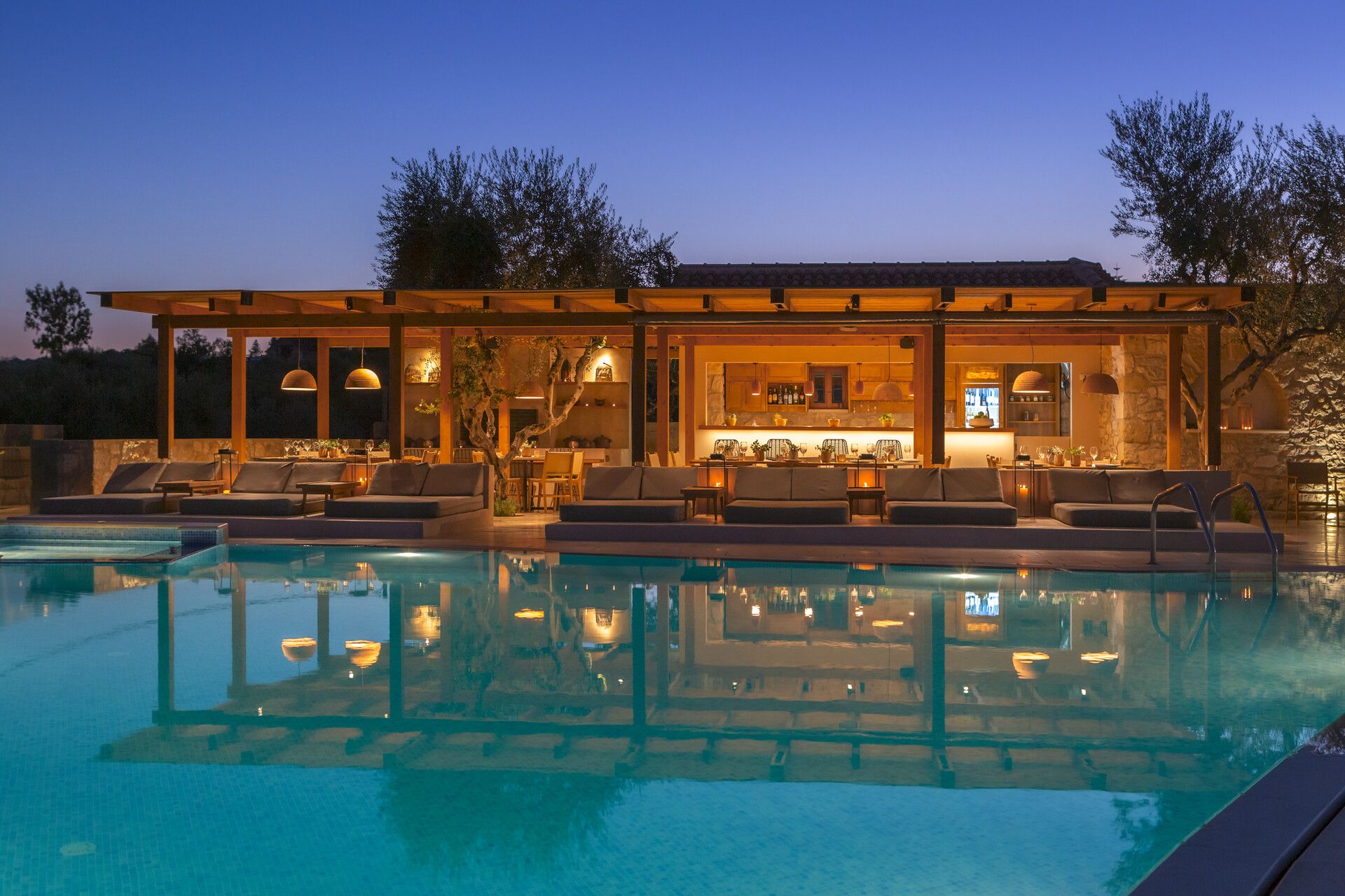 The pool bar lit up at dusk, reflected in the water