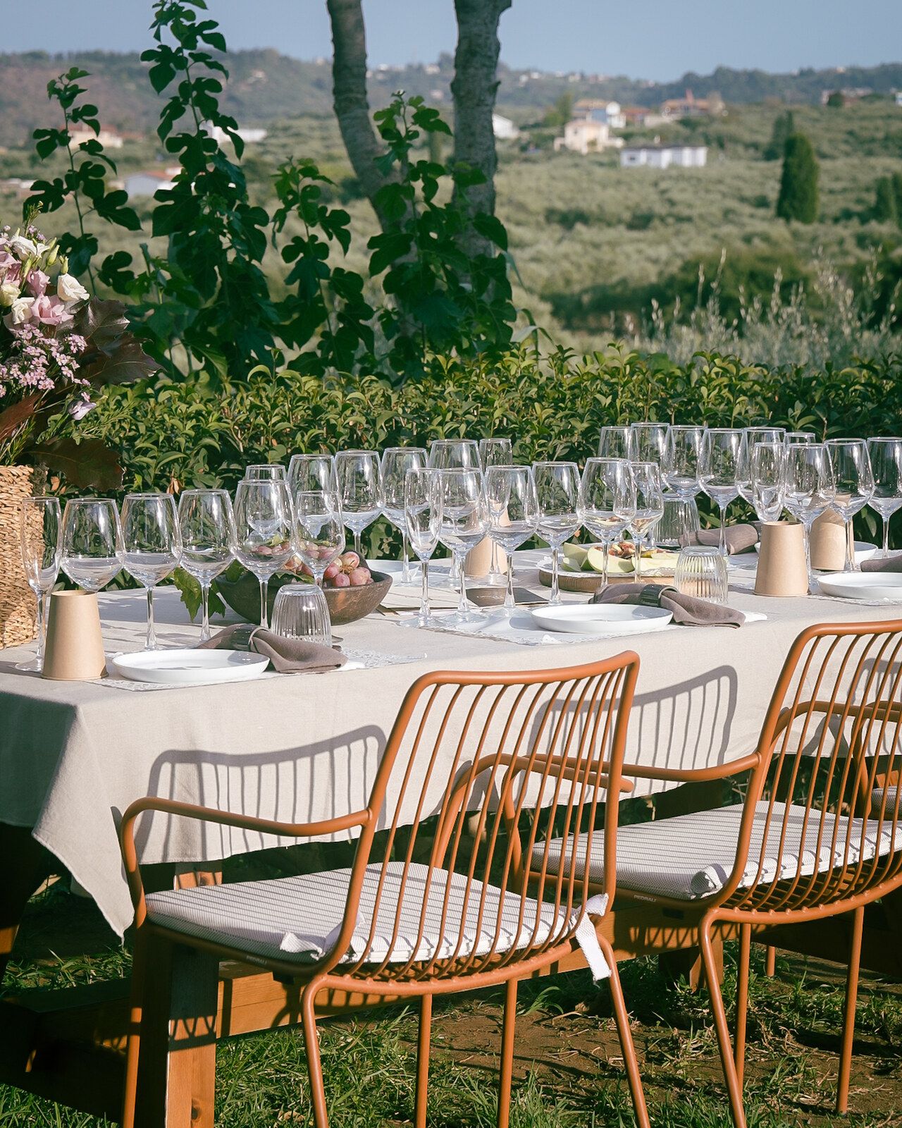 A long table set with wine glasses in the garden, overlooking the sea